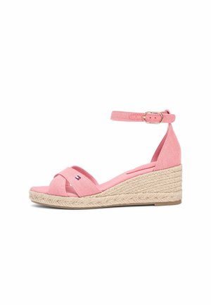 Lyserød kilehæl sandal med ankelrem, flettet jutesål og åben tå med et lille flagemblem på den forreste rem.