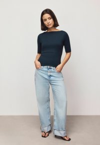 Navy fitted top with a boat neckline, paired with light blue wide-leg jeans featuring rolled cuffs and black sandals.