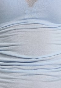 Lichtblauwe stoffen top met een getailleerd ontwerp, voorzien van een geraffineerde textuur en een V-vormige halslijn. Zacht, rekbaar materiaal met een subtiele glans.