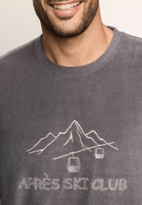 Szary polarowy T-shirt z wzorem górskim, z gondolami, haftowanym napisem "APRÈS SKI CLUB" poniżej. Miękka faktura i luźny krój.