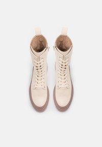 Bottines en cuir beige à bout arrondi, avec un design à lacets, un intérieur rembourré, une fermeture éclair sur le côté et une semelle en caoutchouc marron contrastante.