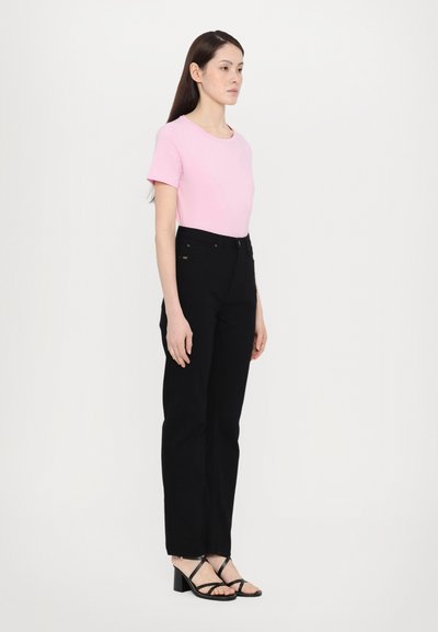 Rosa kortermet skjorte, svarte høyhøyde jeans og svarte stroppede hæler. Lett stoff med en glatt tekstur og tettsittende design.