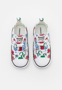 Vita canvas sneakers med färgglada tecknade mönster, med gummisula, svarta detaljer och elastiska remmar för enkel påtagning.