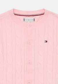 Light pink knitted cardigan with a textured cable pattern, featuring a round neck, five buttons, and a small logo patch on the left side.