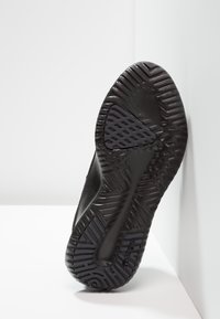 Svart gummisula på sneakers med texturerade mönster och spår för grepp, med en slät kontur och solid konstruktion.