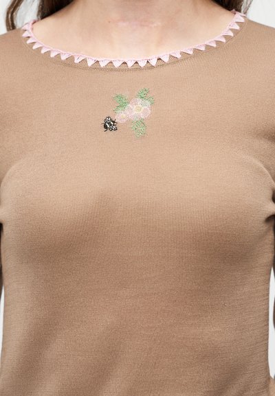 Beige strikket top med lyserød trekantet kant ved rund halsudskæring og lille broderet bi- og blomstermotiv under kraven.