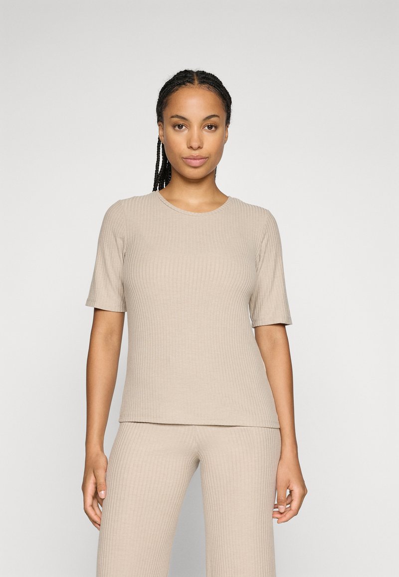 T-shirt beige à côtes avec des manches courtes, un col rond et une coupe ajustée, associé à un pantalon à côtes assorti, mettant en valeur une texture lisse.