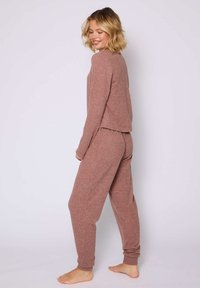 Rippstrick-Loungewear-Set in sanftem Mauve, bestehend aus einem Langarmtop und taillierten Hosen. Mit entspannter Passform und Knöchelabschlüssen für zusätzlichen Komfort.