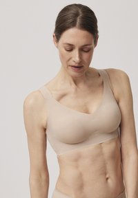 Sostén inalámbrico nude en tejido suave, con un escote en V profundo, tirantes anchos y diseño sin costuras para mayor comodidad y soporte.