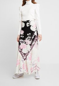 Maxi-Rock mit floralem Muster auf schwarzem Hintergrund, weißen und pinken Akzenten, gestaffeltem Design und einem Saum mit kontrastierendem Rand.
