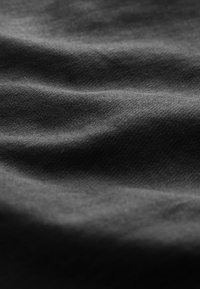 Tissu noir doux avec une texture subtile et de légers plis formant des vagues ombrées à travers la surface.