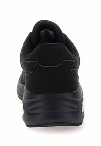 Scarpa sportiva nera con tomaia in tessuto liscia, collarino imbottito e suola spessa in gomma modellata con sottili motivi a onde.