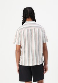 Short-sleeve striped shirt in light fabric, featuring vertical lines in beige, pink, and black. Relaxed fit with a back yoke detail.
