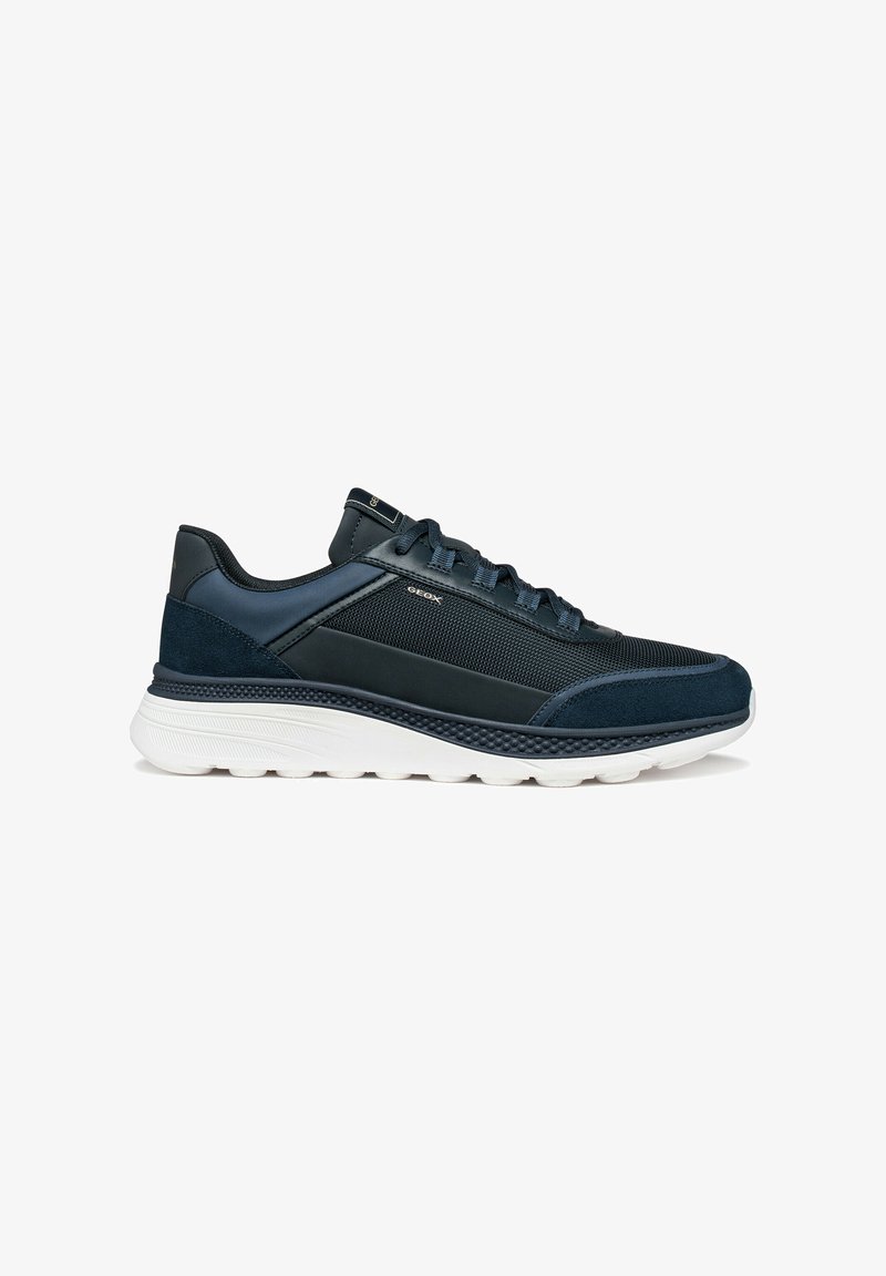 Chaussure de sport bleu marine avec une tige en mesh, des accents en cuir, et une semelle en caoutchouc blanche. Présente un bout arrondi et un talon renforcé.