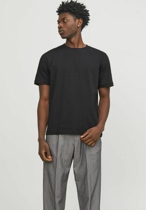 T-shirt in cotone nero con colletto a girocollo e maniche corte, caratterizzato da una vestibilità comoda. Abbinato a pantaloni grigi con righe sottili.