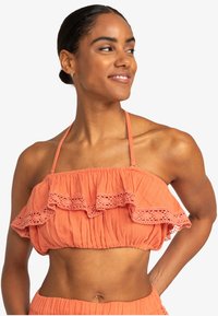 Koralfarvet cropped top med rynket design og blonder, lavet af tekstureret stof. Justerbare stropper og elastisk kant for en god pasform.