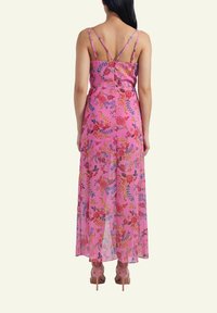 Pink floral maxi dress with adjustable spaghetti straps, transparent fabric, and a layered design. Paired with light pink high-heeled shoes.