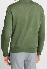 Zelená mikina z bavlněné směsi, s kulatým výstřihem, dlouhými rukávy, žebrovanými manžetami a rovnými lemy.