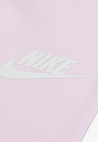 Jasnoróżowa tkanina z dużym białym logo Nike ze wzorem w kształcie łyżwy, teksturowaną powierzchnią, bez dodatkowych wzorów czy akcentów.