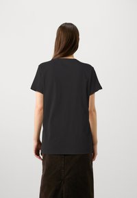 Camiseta negra de manga corta hecha de algodón, con cuello redondo y un corte relajado, con una textura suave y sin patrones visibles.