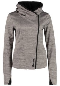 Veste zippée grise pour femme avec fermeture éclair asymétrique sur le devant, col montant haut, doublure intérieure noire, trous pour les pouces dans les manches et logo "Bench.".