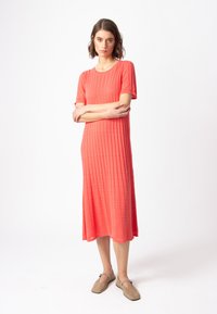 Koralli säärystin mekko lyhyillä hihoilla, polvipituinen, jossa on tekstuuripinta. Yhdistetty vaaleanruskeisiin slip-on kenkiin.