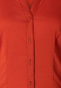 Rode blouse met knopen, gemaakt van een gladde stof, met een V-hals, drie knopen aan de voorkant en een aansluitend ontwerp voor een gestroomlijnde uitstraling.