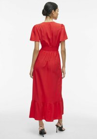 Červené maxi šaty s krátkymi puff rukávmi, elastickým pásom, volánkovým spodným okrajom, hladkou saténovou textúrou a skromným okrúhlym výstrihom.