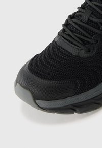 Μαύρο αθλητικό παπούτσι με υφασμάτινο επάνω μέρος από υφή, καουτσούκ σόλα και ενισχυμένο τμήμα δαχτύλου, με ταιριαστά κορδόνια και διακριτικά στοιχεία branding.