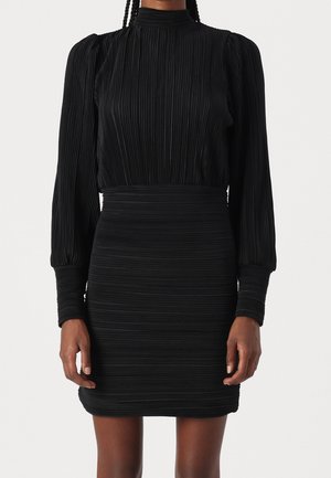 Černé plisované šaty s vysokým výstřihem, dlouhými nafouklými rukávy a přiléhavým pasem. Texturovaná látka s vodorovnými pruhy po celém povrchu.