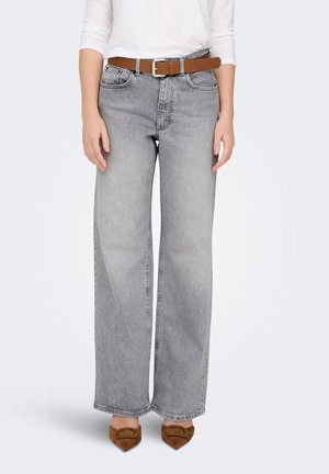 Plašas pelēkas bikses ar raibu rakstu, priekšpusē ar kabatām un brūnu ādas jostu. Modelis valkā brūnas kurpes ar papēžiem.