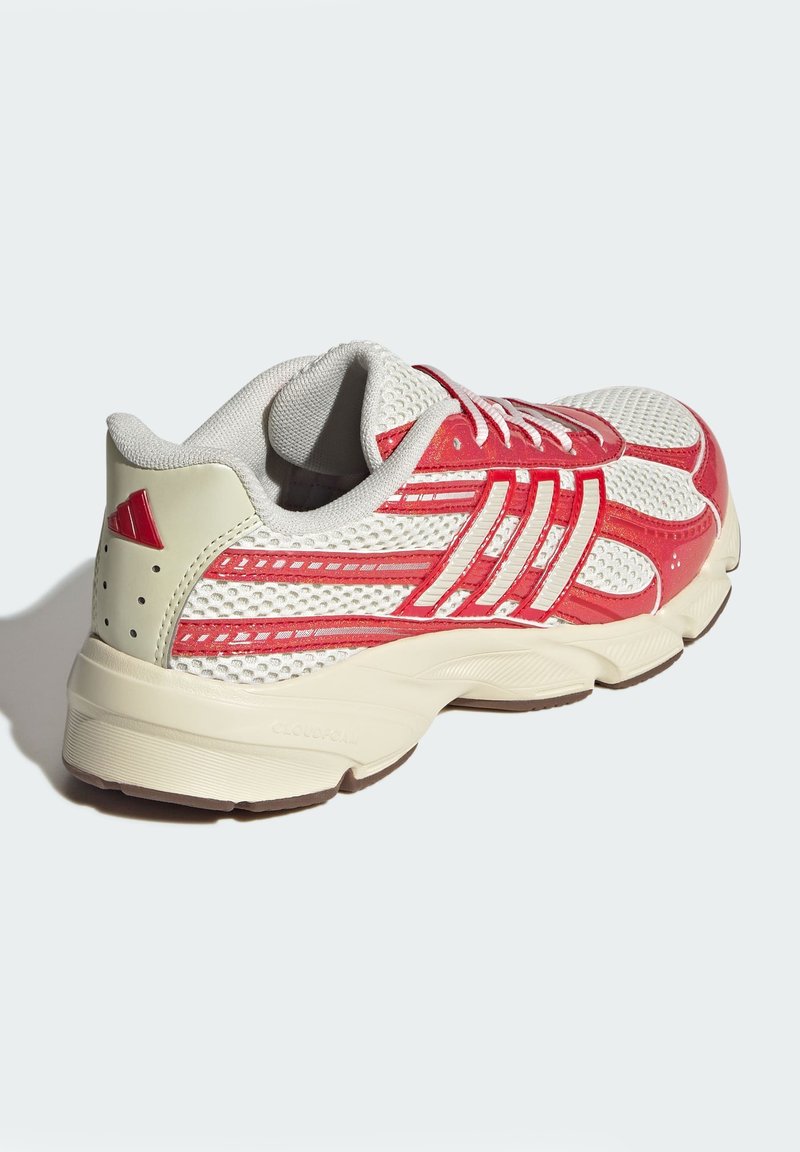 Scarpa sportiva rossa e bianca con tomaia in mesh, colletto imbottito e suola in gomma con scanalature distintive e un piccolo logo rosso sul tallone.