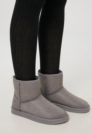 Stivali alla caviglia grigi con tomaia texturizzata e luccicante, punta rotonda e suola in gomma, abbinati a leggings neri a coste.