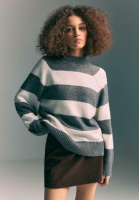 Maglione a righe con bande grigie e bianche, colletto e polsini a coste, abbinato a una gonna in velluto a coste marrone. Texture liscia e vestibilità comoda.