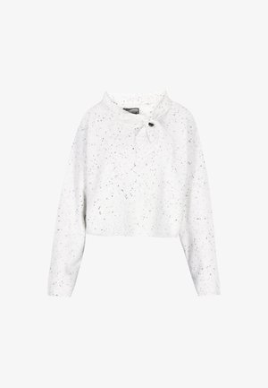 Bela skrajšana jopica s pikčasto črno vzorcem, ki ima ovratnik in zavezovanje, ki je na sprednji strani pritrjeno z gumbom. Mehak tekstur.