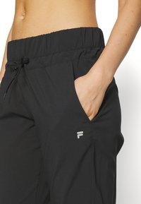 Melnas sporta bikses ar elastīgu jostu, regulējamu šņorīti, sānu kabatām un mazu logo uz augšstilba. Gluda, viegla auduma.