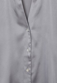 Blusa in satin grigio con scollatura a V e cinque bottoni perlacei lungo il davanti. Tessuto liscio con una leggera lucentezza.
