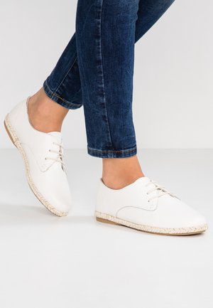 Hvide lædersko med glat finish, rundet tå, snørebånd og flettet jutesål. Kombineret med mørke denimjeans.
