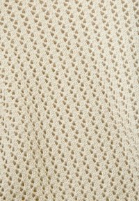 Strickstoff in Beige mit einem offenen Rautenmuster. Weiche Textur mit erhabenen Stichen, ideal für atmungsaktive Kleidungsstücke oder Accessoires.