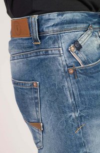 Lichtblauwe denim jeans met een gestructureerde afwerking, een bruine leren label en oranje stiksels, met meerdere zakken en knoopdetails.