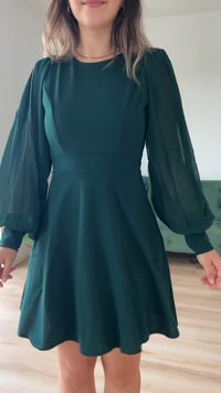 Zöld, rövid ujjú ruha, melynek szűkített derékrésze és tágas, áttetsző puffujjai vannak. Sima textúra, kimenetel szoknyával.