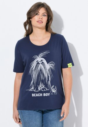 T-shirt bleu marine avec un graphique d'une créature poilue à longs cheveux et d'un crabe, avec le texte "BEACH BOY" en blanc en dessous de l'image.