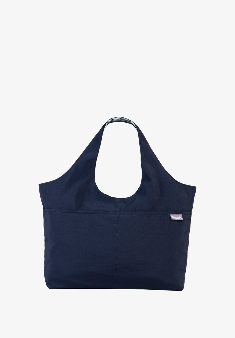 Marineblauwe stoffen draagtas met een grote open bovenkant, brede schouderriem en voorvak. Bevat een contrasterend interieurpatroon en logo-label.