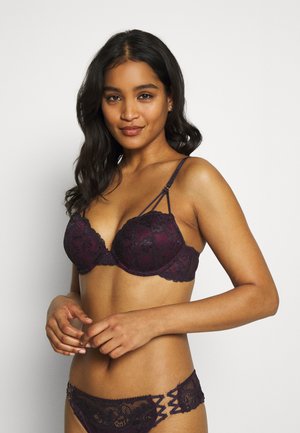 Spitzen-BH und passende Slips in tiefem Burgundy. Der BH hat Bügel, gewellte Kanten und Riemendetails. Die Slips haben Spitzelemente.