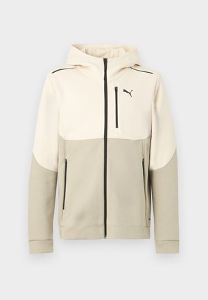 Zweifarbiger beige Kapuzenpullover mit Reißverschluss, vorderer Brusttasche, Seitentaschen, schwarzen Reißverschlüssen und kleinem Puma-Logo auf der linken Brust.