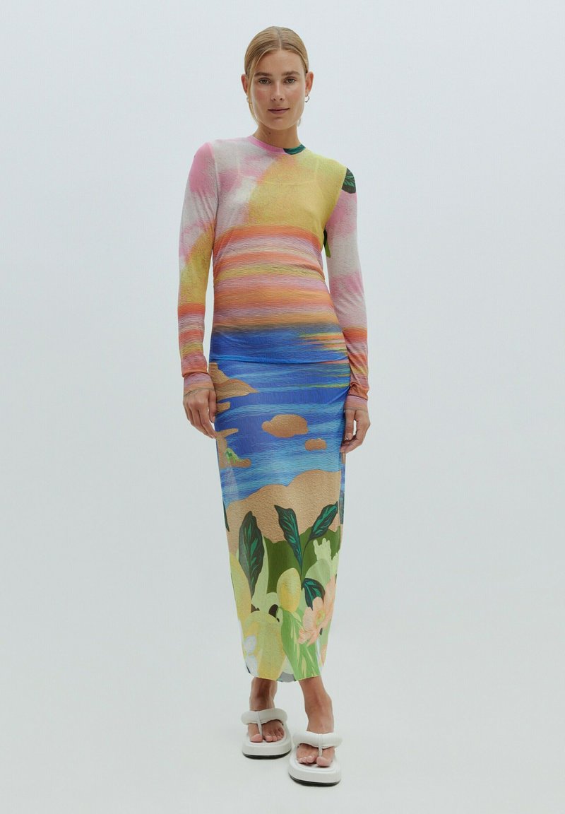 Robe à manches longues colorée avec un design de coucher de soleil dégradé en rose, jaune et bleu, présentant un imprimé floral tropical à l'ourlet.