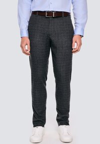 Ciemnoszare w kratę spodnie z delikatnym wzorem, zestawione z brązowym paskiem i białymi sneakersami. Gładki materiał i fason slim-fit.