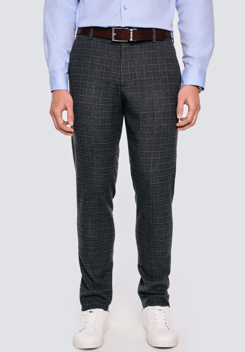 Ciemnoszare w kratę spodnie z delikatnym wzorem, zestawione z brązowym paskiem i białymi sneakersami. Gładki materiał i fason slim-fit.