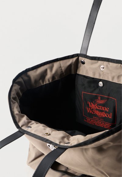 Μπεζ τσάντα ώμου με μαύρες λαβές, μαύρη εσωτερική τσέπη με κόκκινο λογότυπο Vivienne Westwood και κείμενο για τη δεοντολογική μόδα στην Κένυα.