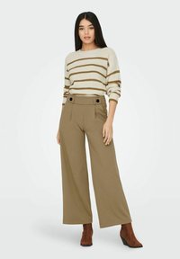 Beige en bruin gestreepte gebreide trui met een ronde hals, gecombineerd met hoge taille, wijde olijfgroene broek met knoopdetails.